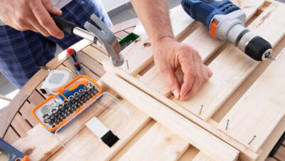 Мастер забивает гвоздь молотком в деревянную полку